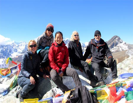 trekkers taking group photo at the cho la pass top, blue sky in a clear day and prayer flags.