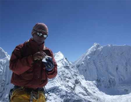 A climber on the summit of Island Peak with proper gear and the blue sky.