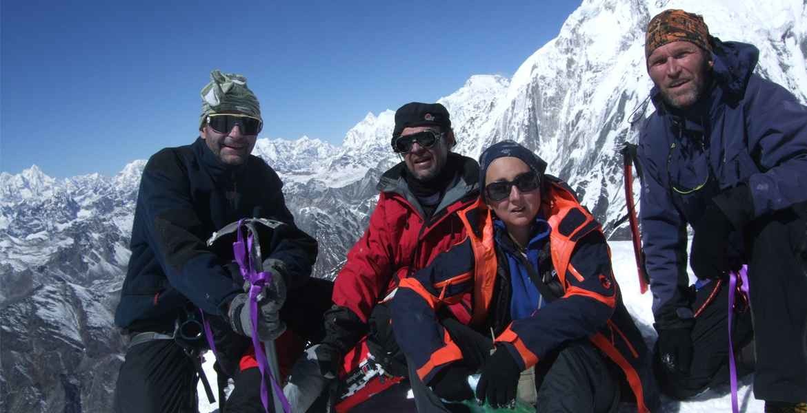 Climbers on the summit of Island Peak with proper climbing gear and clothing, high mountain views, and the blue sky.