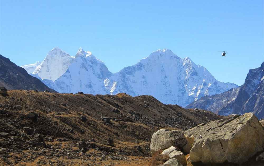 Magnificent views of Mt.Thamserku and Khangteka in the Everest Himalayas and a helicopter flying above the mountains during the Everest Base Camp Helicopter Return trek.