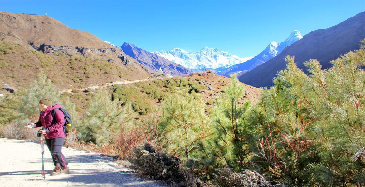 a female trekker with trekking gear on the EBC trail, blue sky and the everest himalaya in a clear day in october.