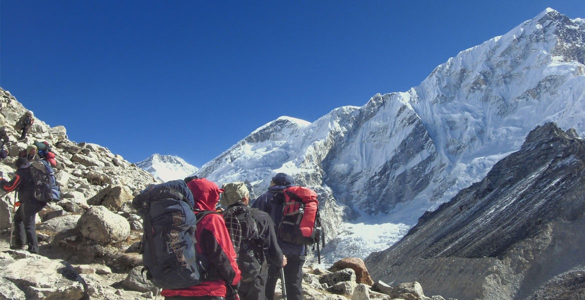 everest base camp trekkers crossing a glacier before reaching the last camp, beautiful everest himalaya on the side.