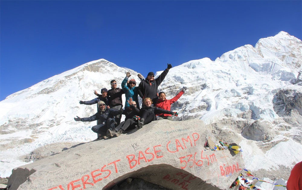 trekkers are taking group photo after successful everest base camp trek, beautiful view of the everest mountains with blue sky on a clear day.
