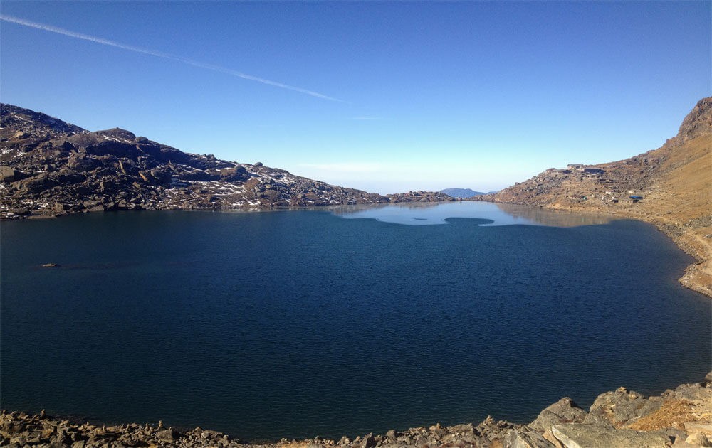 beautiful gosaikunda lake, blue sky and trekking lodges on the side in gosaikunda lake trek.