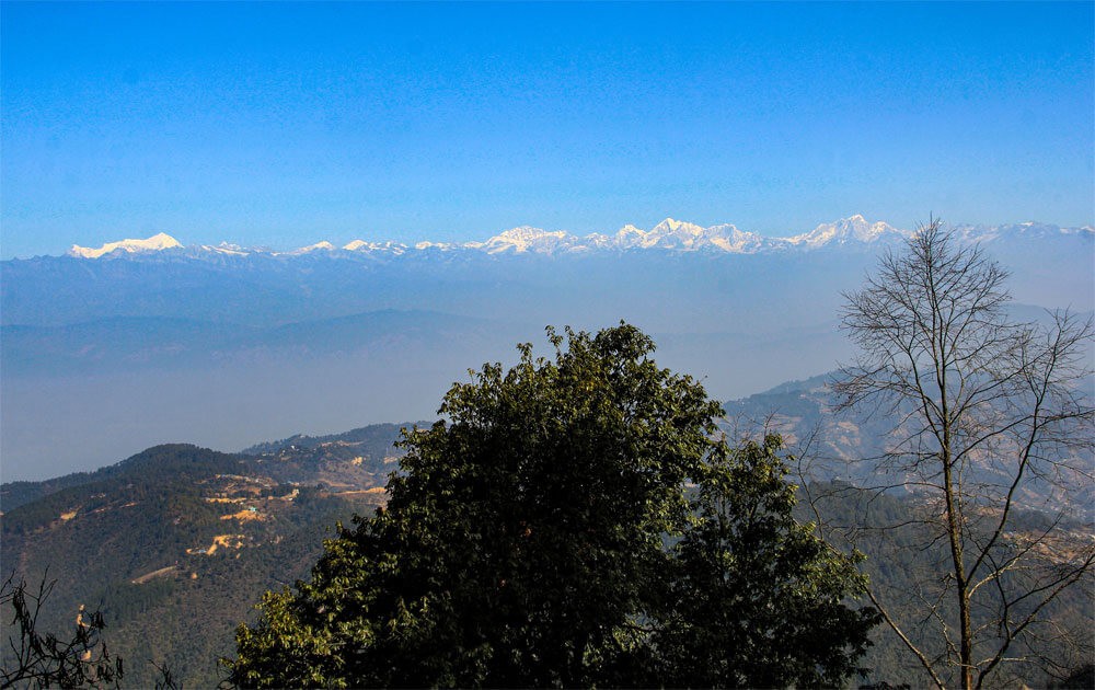 panoramic view of white mountains with the blue sky on a clear day from phulchoki hill on the phulchoki hike.
