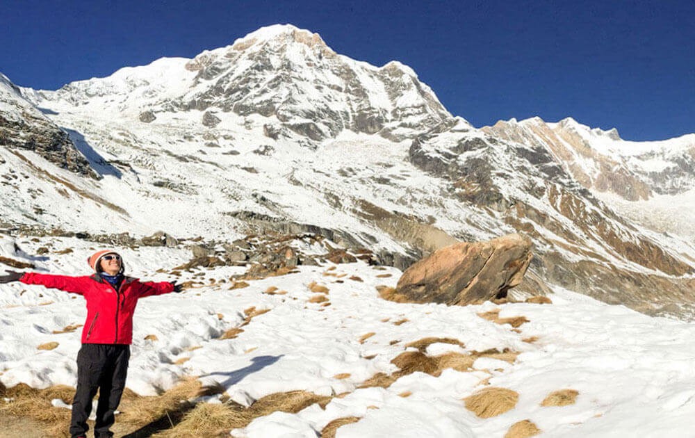 bright view of annapurna with blue sky on a clear day and a trekkers is celebrating successful trip at the base camp on short annapurna base camp trek